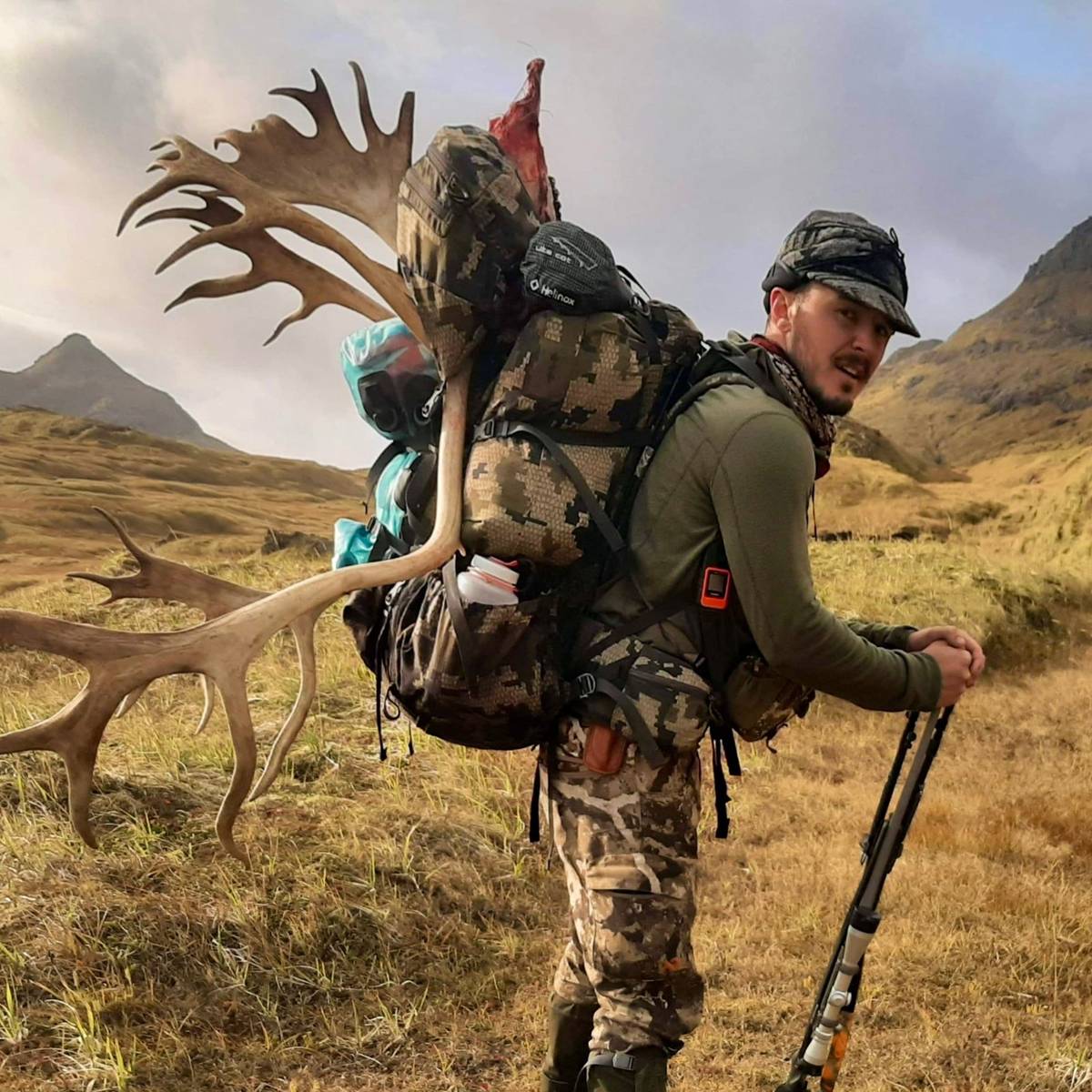 Backpack hunter packing out Caribou antlers through the Adak mountains