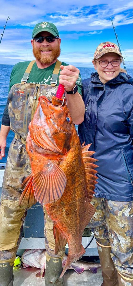Couple on the boat holding a huge red Rockfish in bright sun