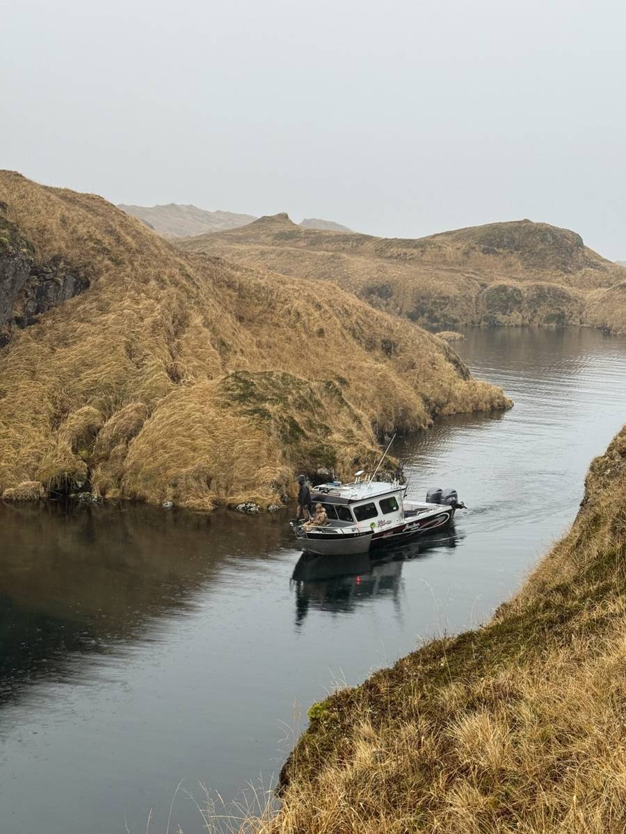 Lodge boat anchored in a narrow Adak fjord cove